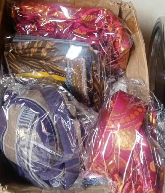 Box of aso-oke and lace fabrics wrapped in clear plastic